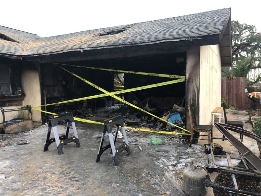 Fire-damaged house with a charred garage opening
